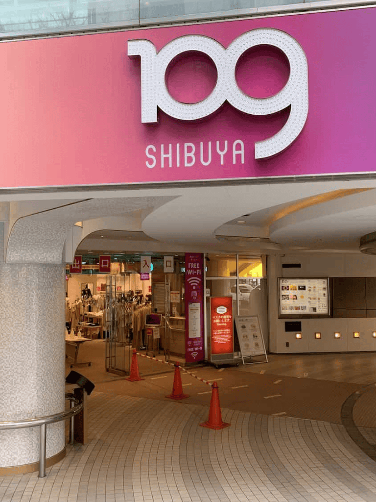Bright pink sign reading "109 SHIBUYA" at shopping complex entrance, modern outdoor shopping, popular Tokyo shopping destination.