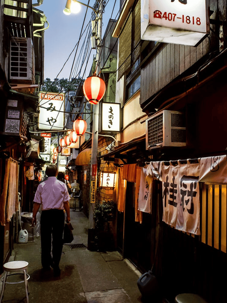 Traditional Japanese alleyway with lanterns and restaurant signs, vibrant street scene in Tokyo.