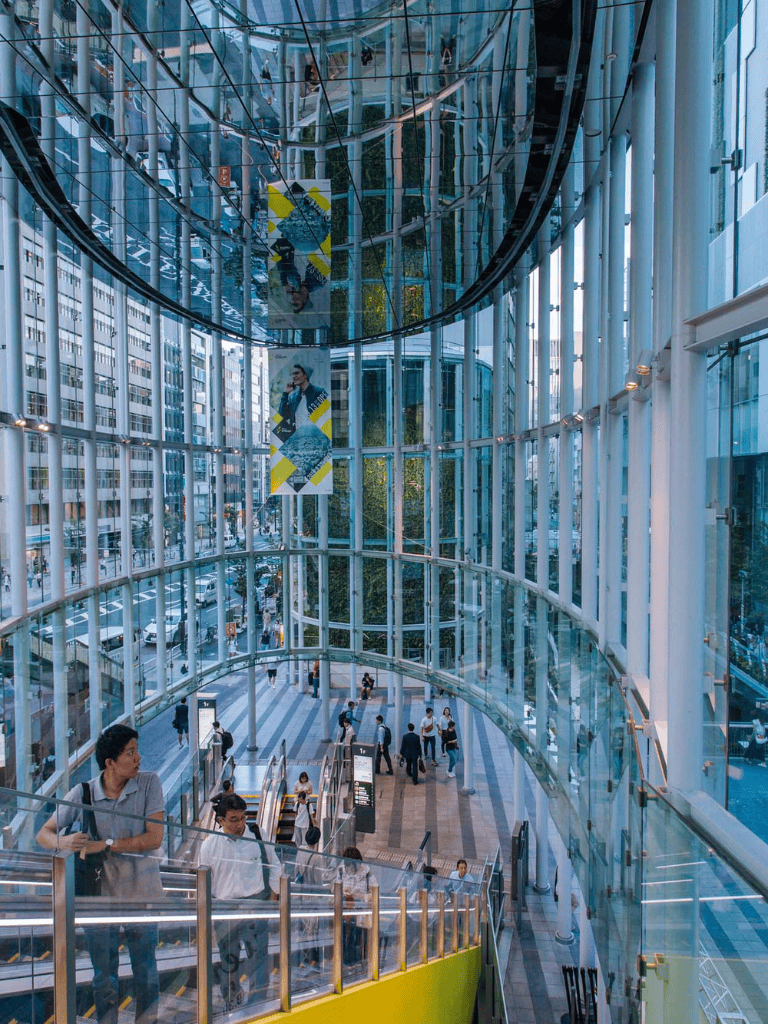 Bright modern glass interior of Quest for Directions building with people using escalators and walking.