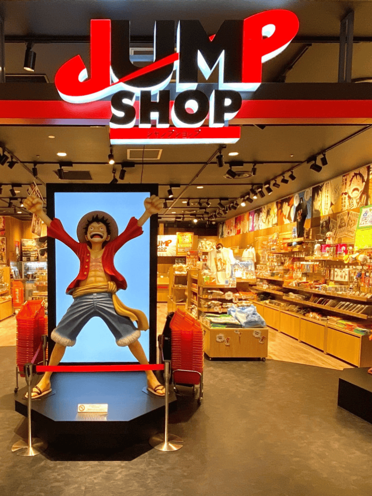 Jump Shop store entrance with One Piece character statue and colorful merchandise displays.