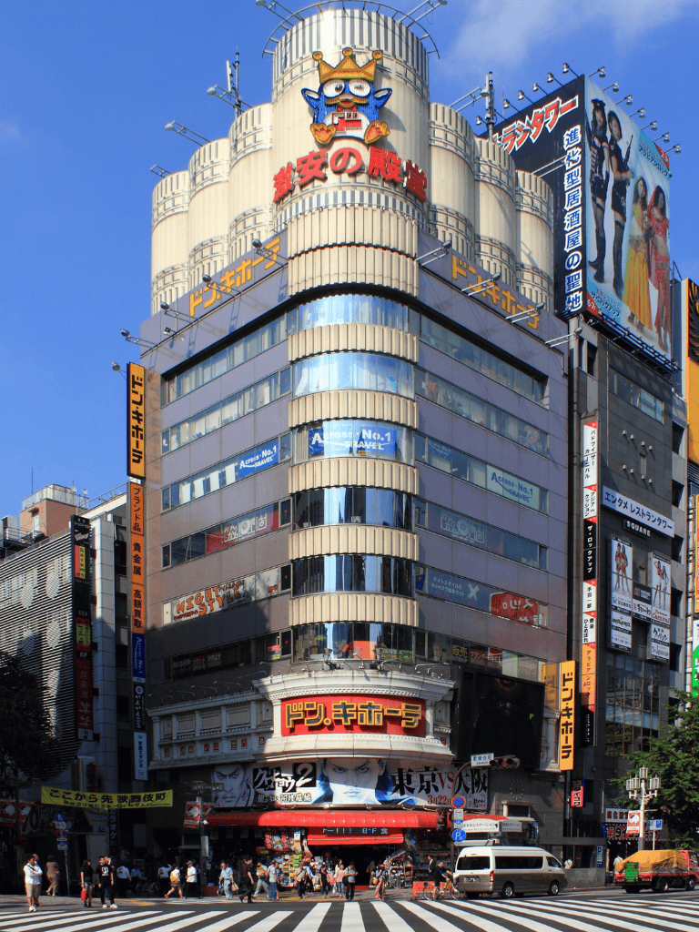 Vibrant Tokyo building with neon signs and large anime-themed advertisements.
