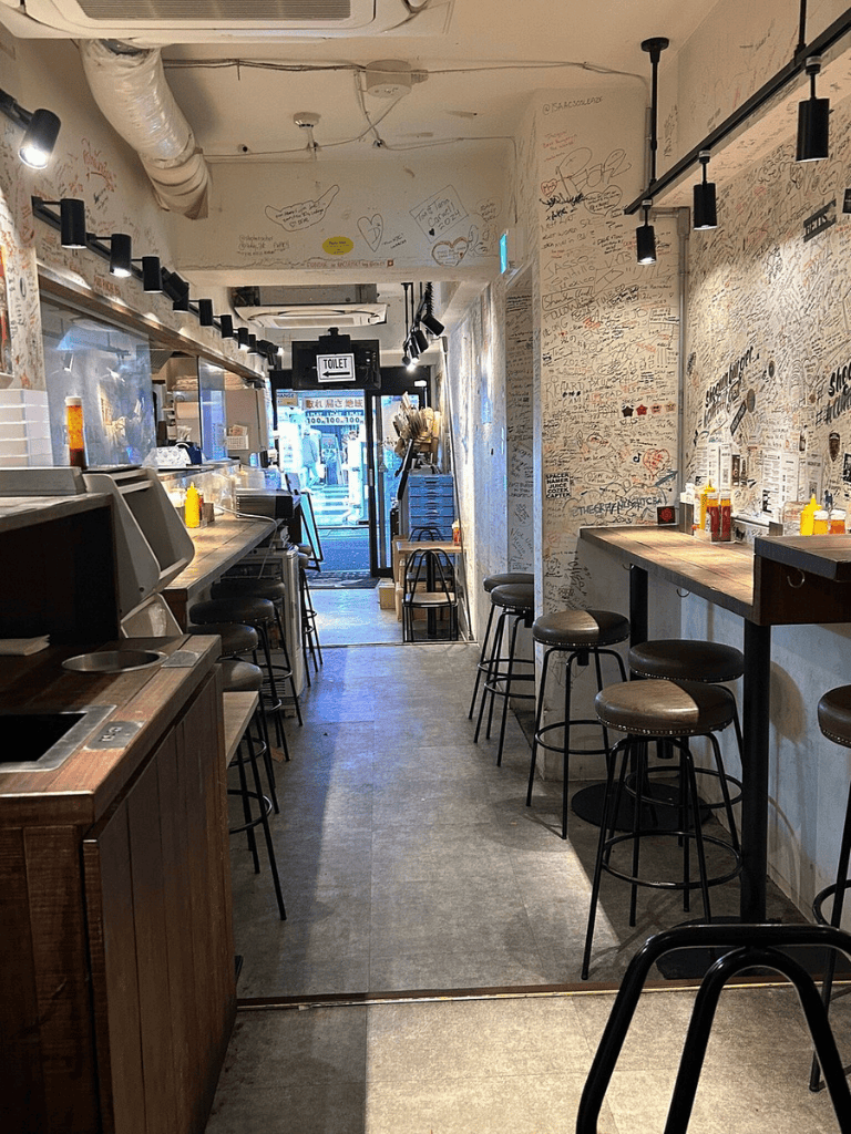 Cozy restaurant interior with graffiti-covered walls, bar seating, and modern lighting for a casual dining experience.