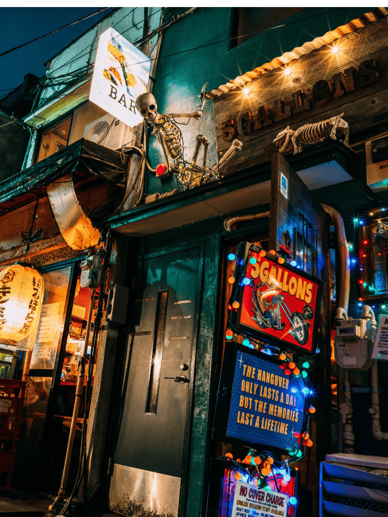 Skeleton decoration on bar exterior, vibrant neon signs at night, lively nightlife atmosphere.