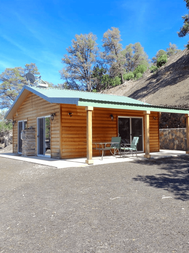 Cozy wooden cabin with outdoor patio in a scenic mountain setting.