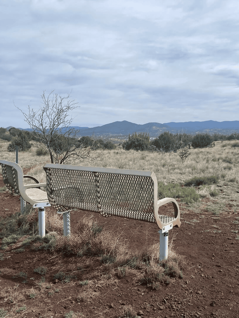 Empty park benches overlooking a scenic mountainous landscape with cloudy sky.