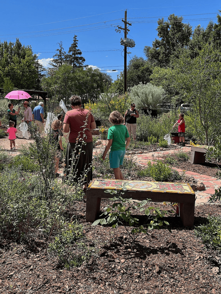 Kids and adults enjoying a garden tour with lush greenery and vibrant plants.