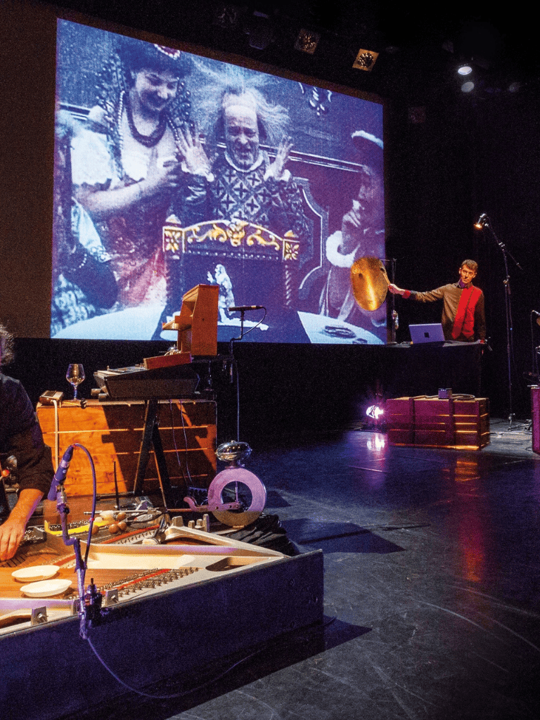 Colorful musical performance with projections and live instruments at QuestForDirections event, blending art and culture.