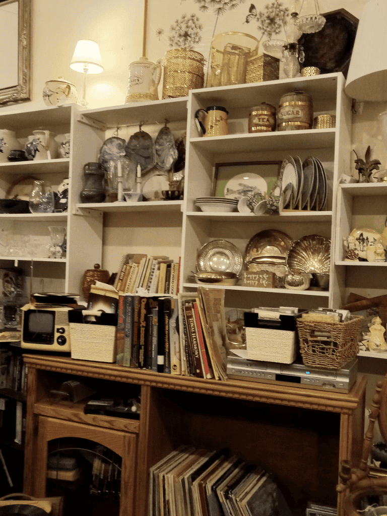 Vintage kitchenware and antique collectibles arranged on white shelves and wooden furniture at QuestForDirections.