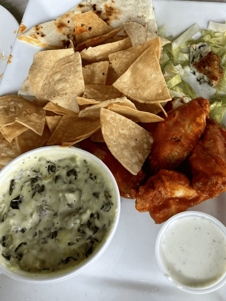 Crispy chicken wings with tortilla chips, creamy herb dipping sauce, and side salad, perfect for a delicious meal.
