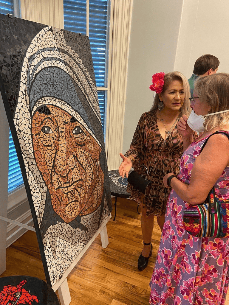 Woman explaining mosaic art to visitors at QuestForDirections event.