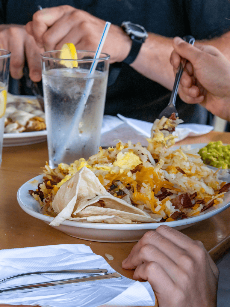 Fresh Mexican breakfast with chips, guacamole, and water on a wooden table.