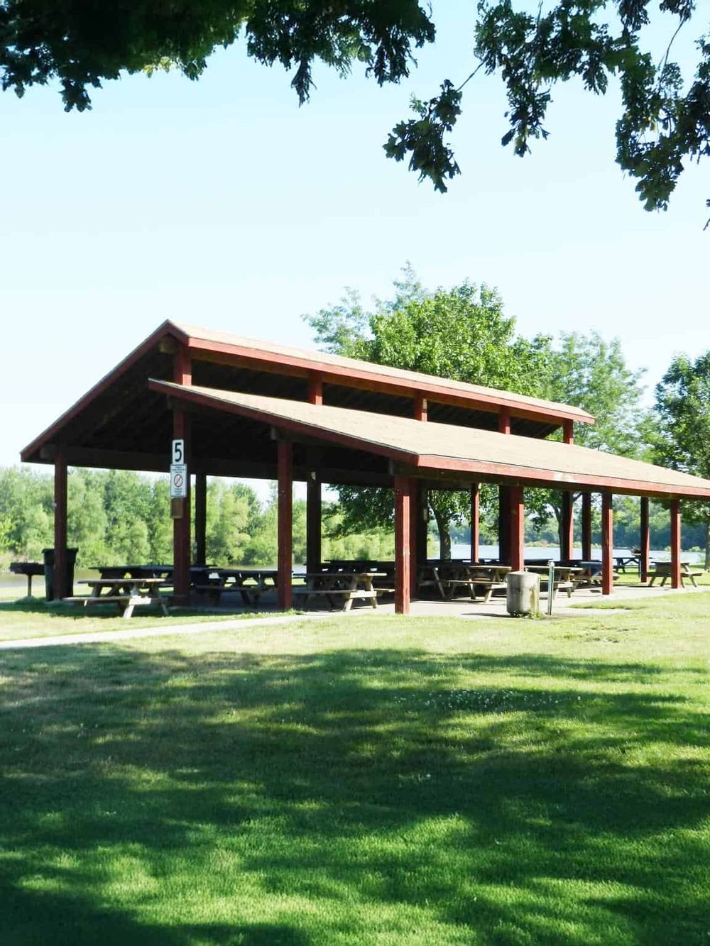 Spacious outdoor picnic shelter at Quest For Directions park with picnic tables and lush green surroundings.