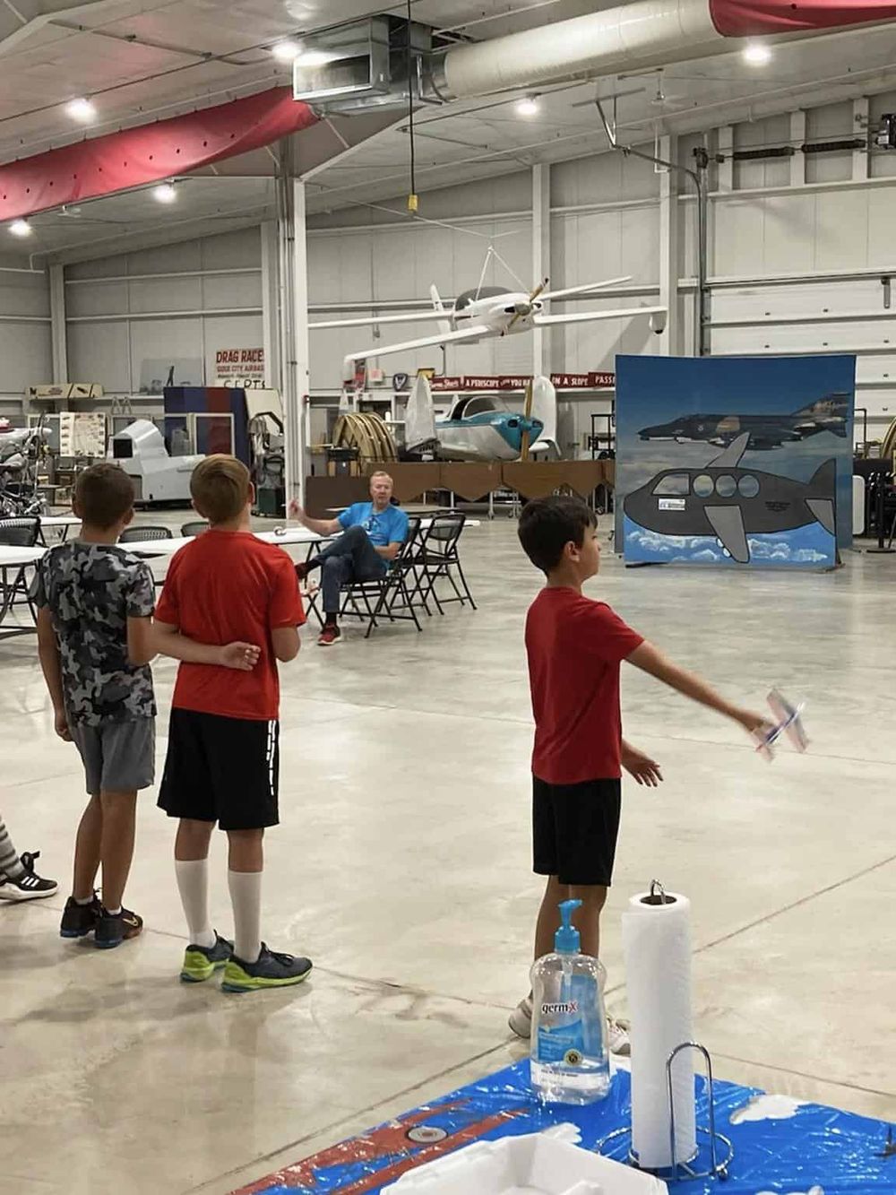 Drop Test: Three kids watch a demonstration at Quest For Directions, an aviation museum with aircraft exhibits and interactive activities.