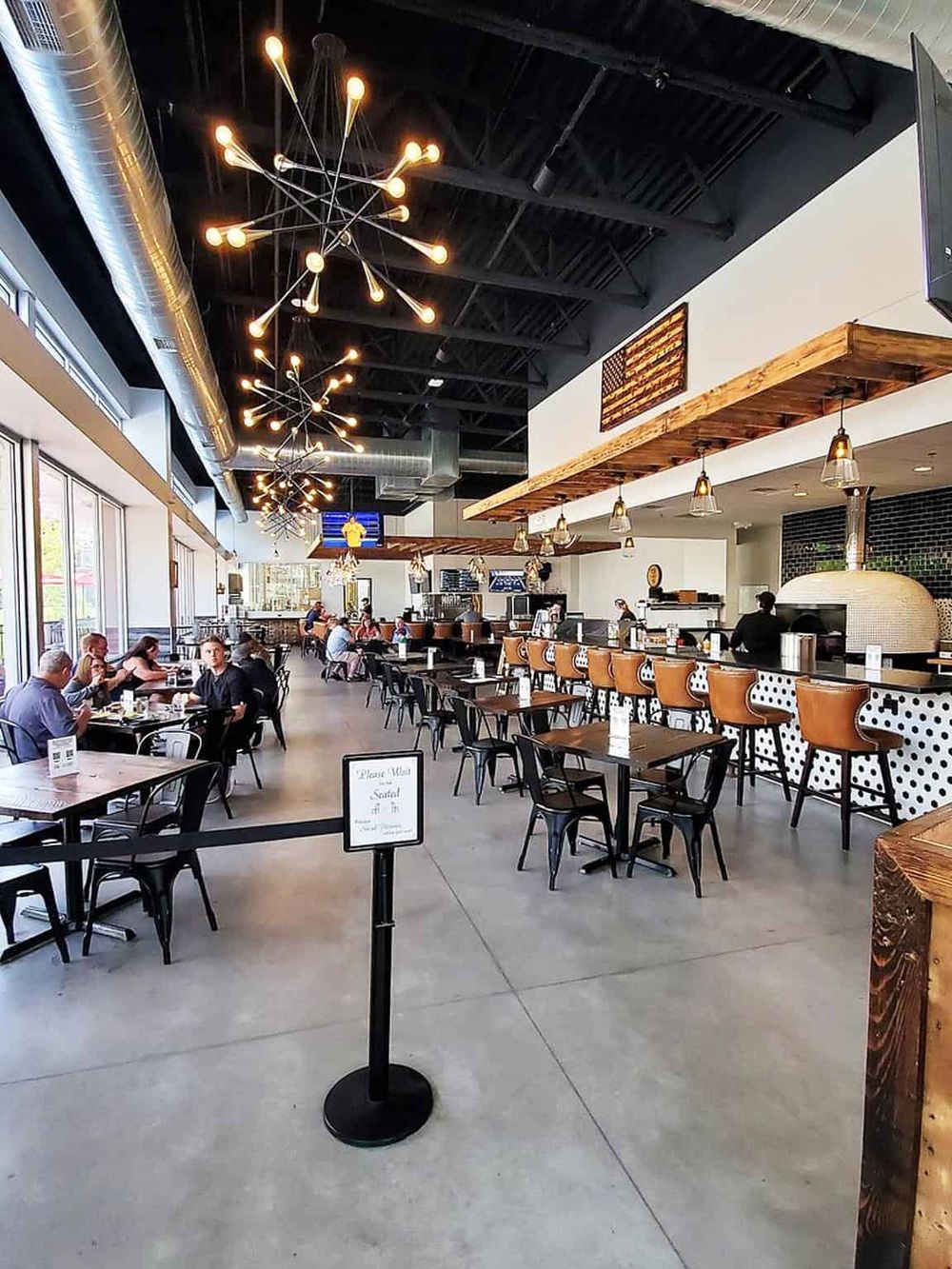 Modern restaurant interior with stylish lighting, bar seating, and a spacious dining area for guests.