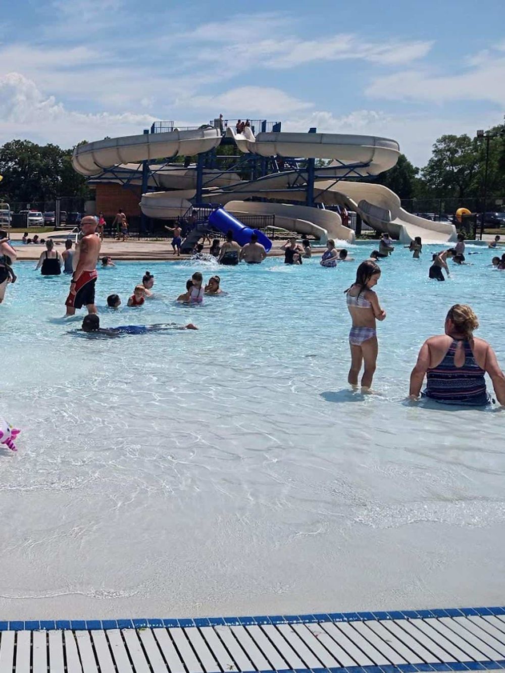 Colorful water park with slides and kids swimming and playing in the pool.