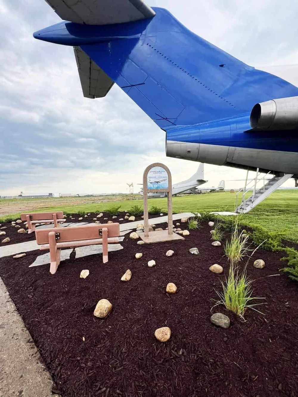 Colorful airplane tail at outdoor aviation museum with benches and sign.