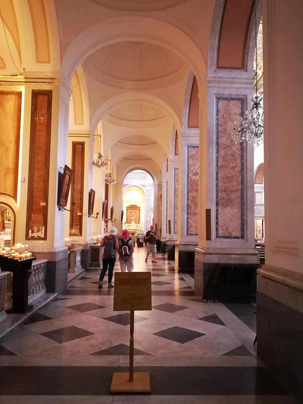 Elegant church interior with marble pillars and chandeliers, showcasing architecture and historical art.