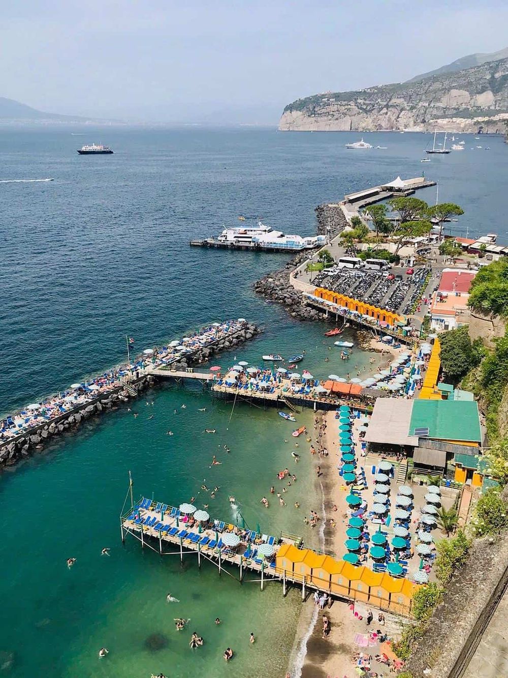 Picturesque seaside harbor with boats, beach, and vibrant umbrellas showcasing coastal travel destinations.