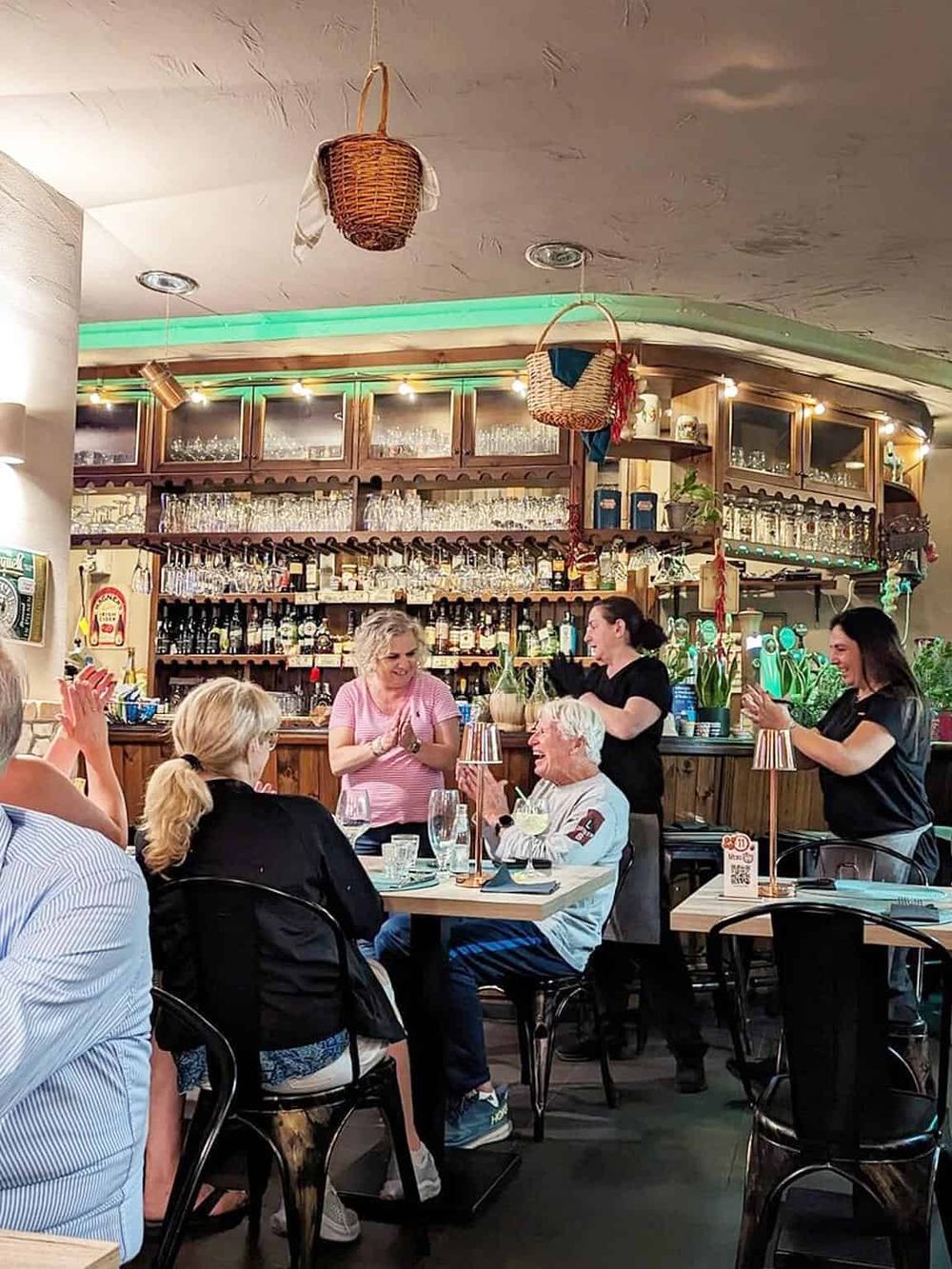 Happy customers enjoying drinks at a cozy restaurant bar, with friendly staff and vibrant ambiance.