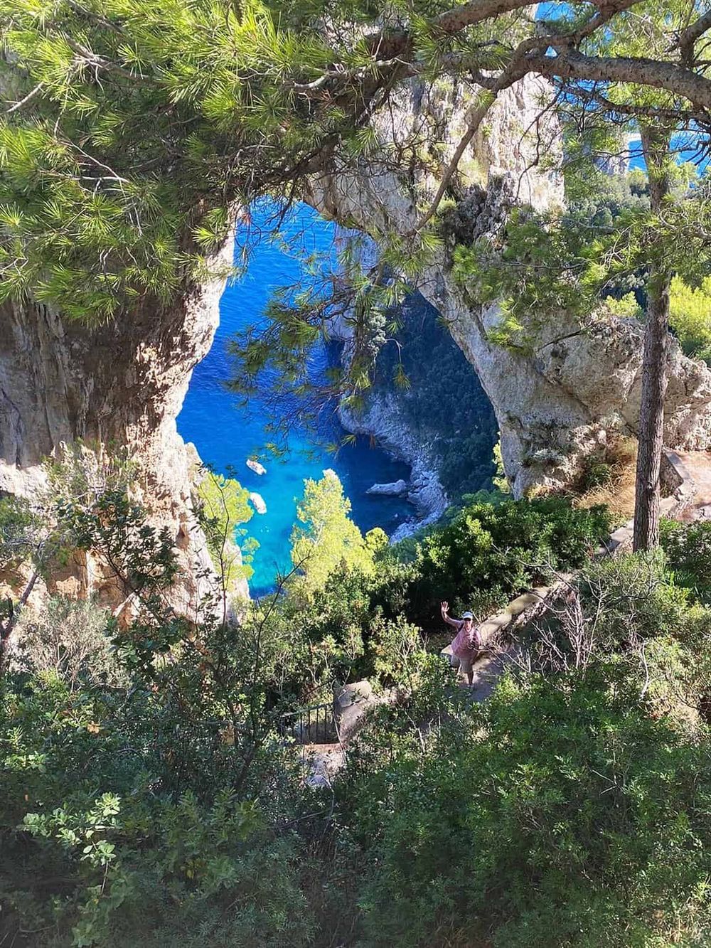 Breathtaking view of turquoise water through natural rock arch surrounded by lush green forest.