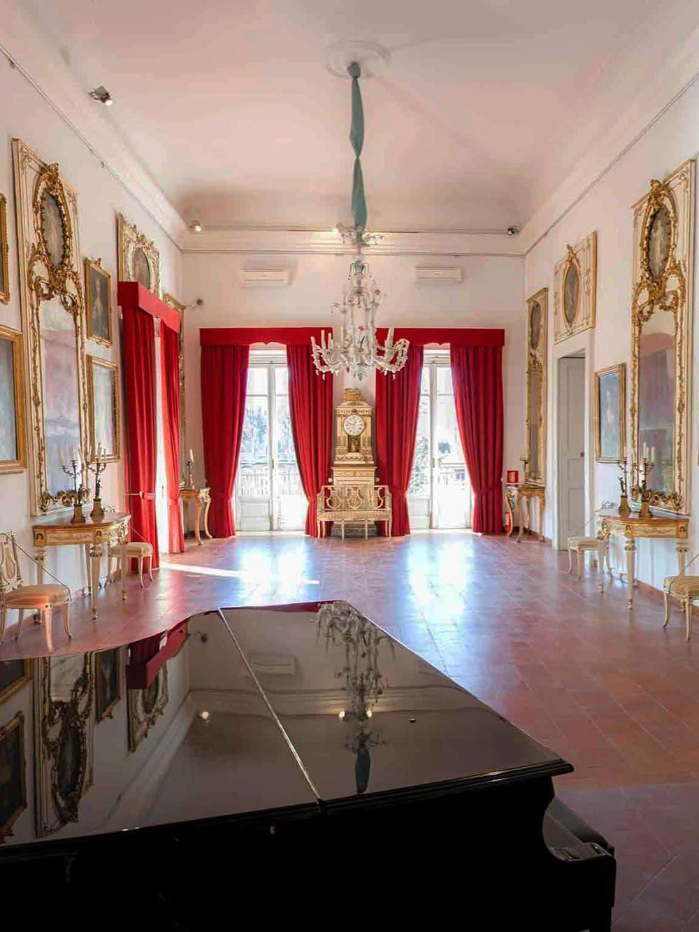 Elegant historic interior of a luxury mansion with red curtains and gold accents.