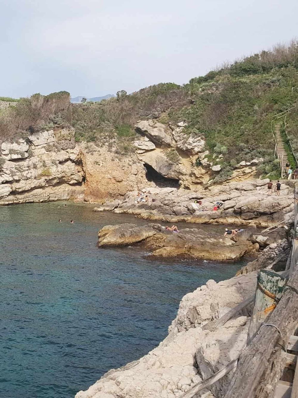 Secluded beach with rocky coastline and hiking stairs at top, popular for relaxation and scenic views.