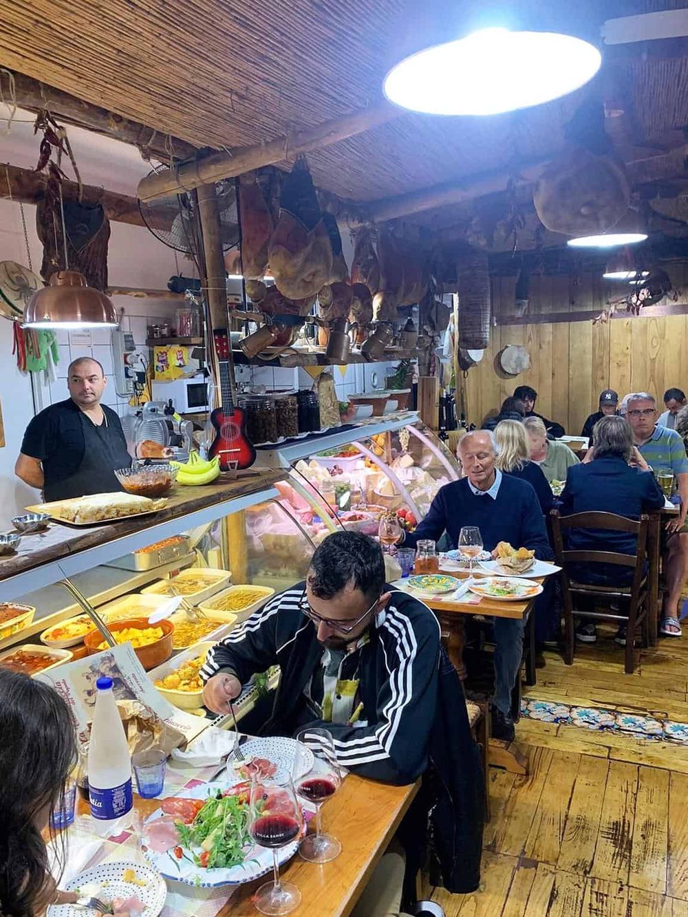 Cozy restaurant interior with patrons enjoying Italian cuisine, rustic decor, and wooden accents, perfect for authentic dining experiences.