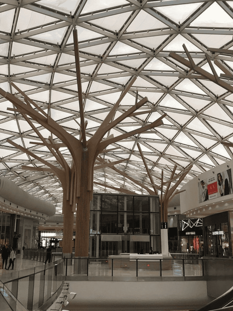 Modern shopping mall interior with architectural tree-inspired ceiling design.