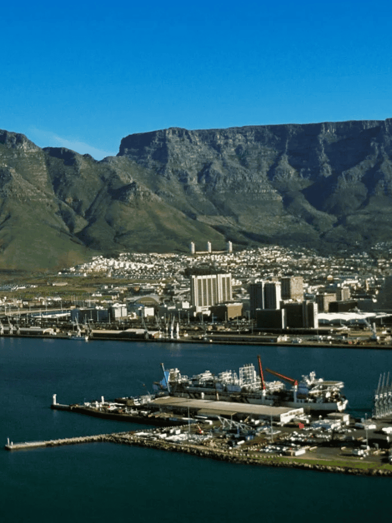 Vibrant cityscape with mountain backdrop and busy harbor in Cape Town, South Africa.