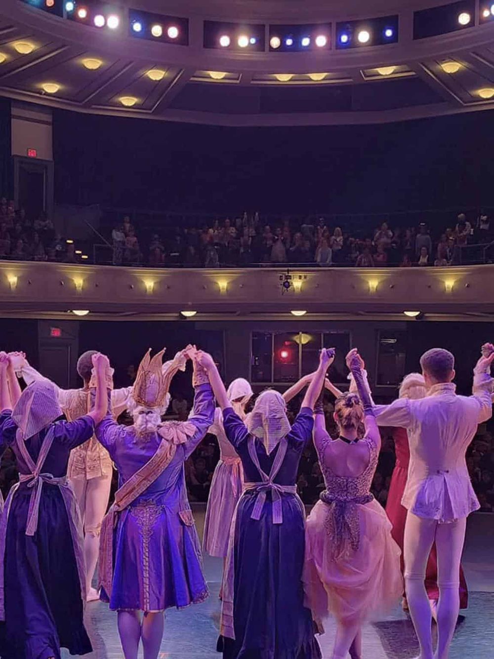 1. Diverse performers in vintage costumes on stage during a theatrical production.