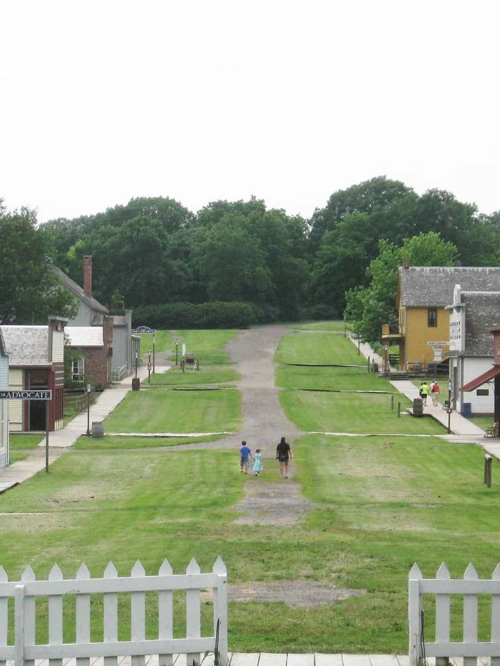 Historic small-town street with shops and greenery, showcasing a charming, family-friendly atmosphere.