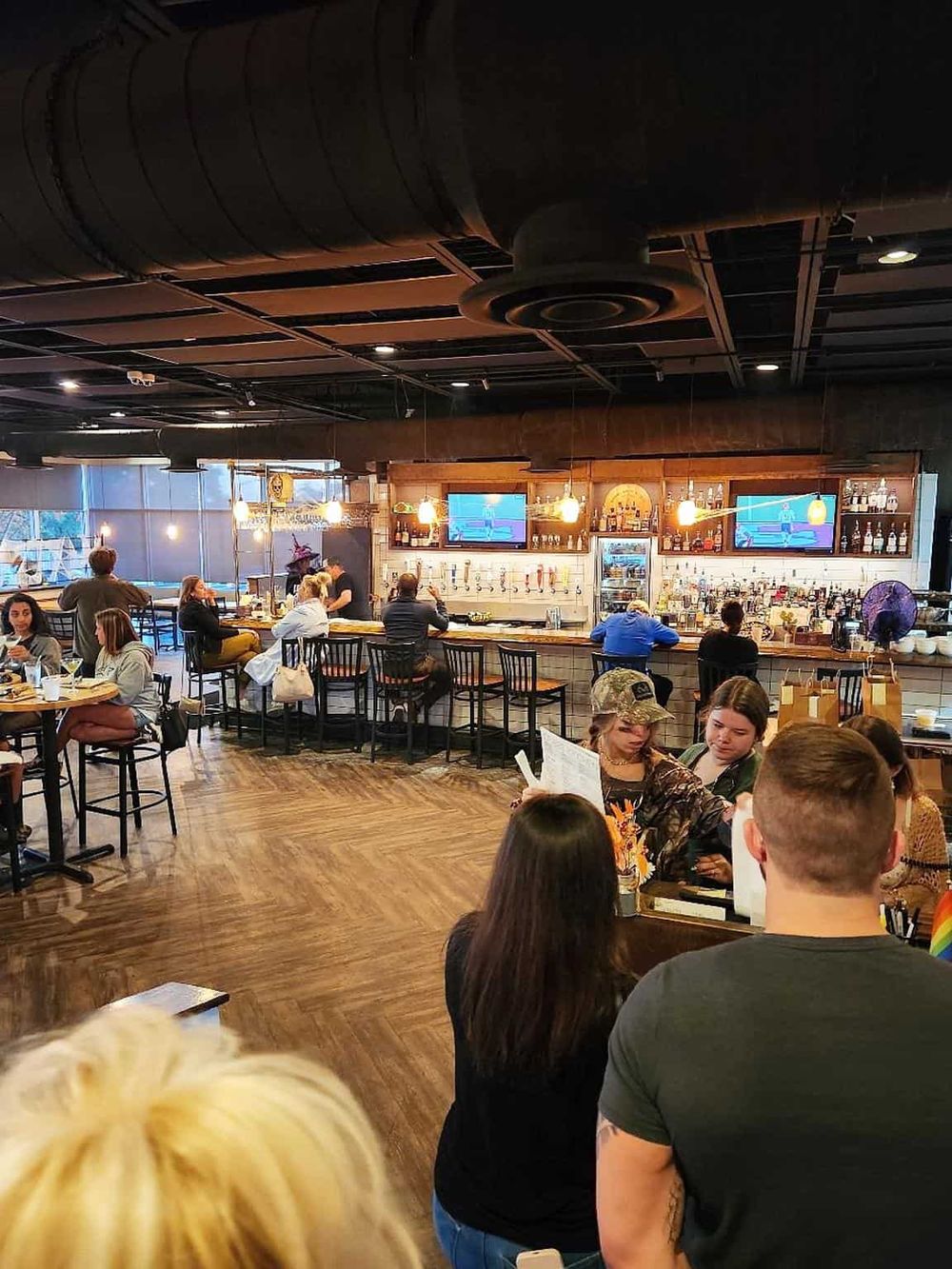 Cozy modern bar and restaurant interior with customers enjoying drinks and food ambiance.