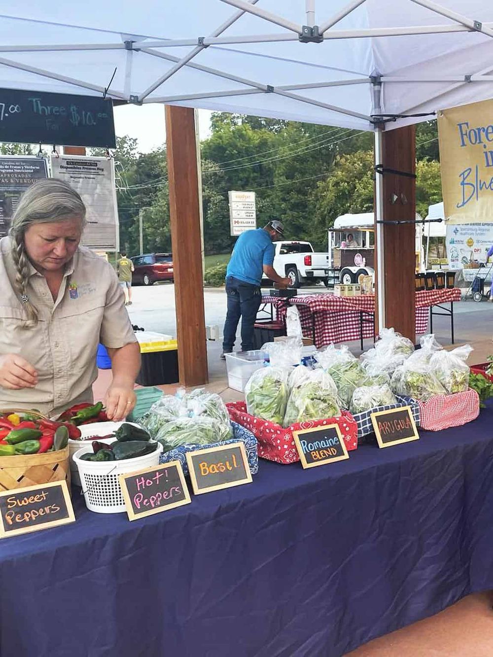 Fresh local produce stand at a farmer's market with colorful peppers and greens.