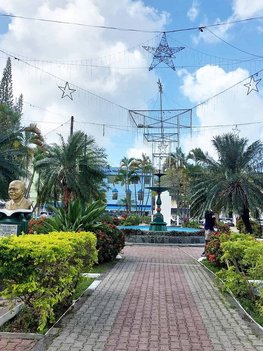 Colorful city square with palm trees, festive star decorations, fountain, and monument, perfect for local sightseeing and outdoor activities.