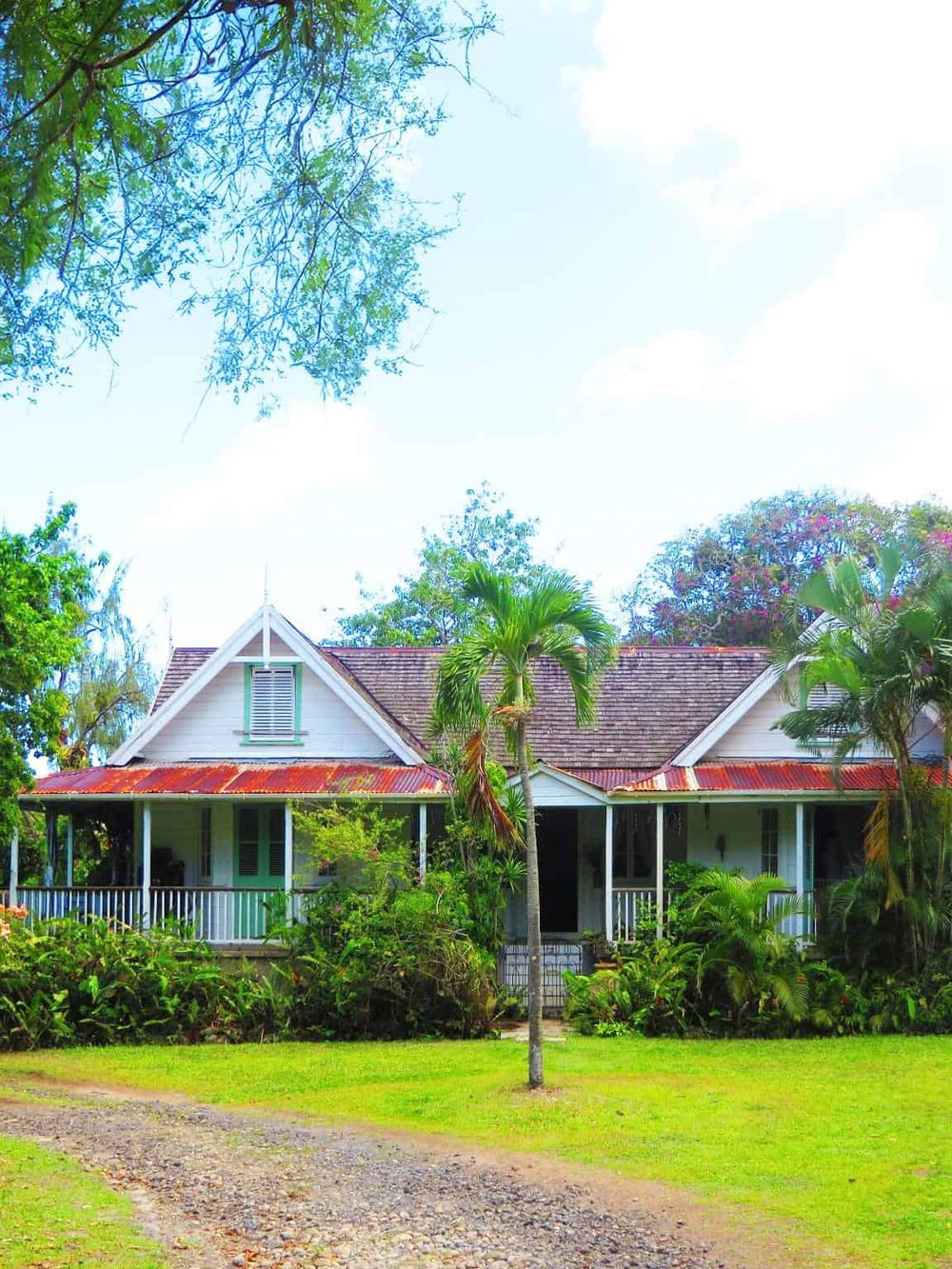 Charming vintage house surrounded by lush greenery and tropical plants, ideal for a nature retreat.