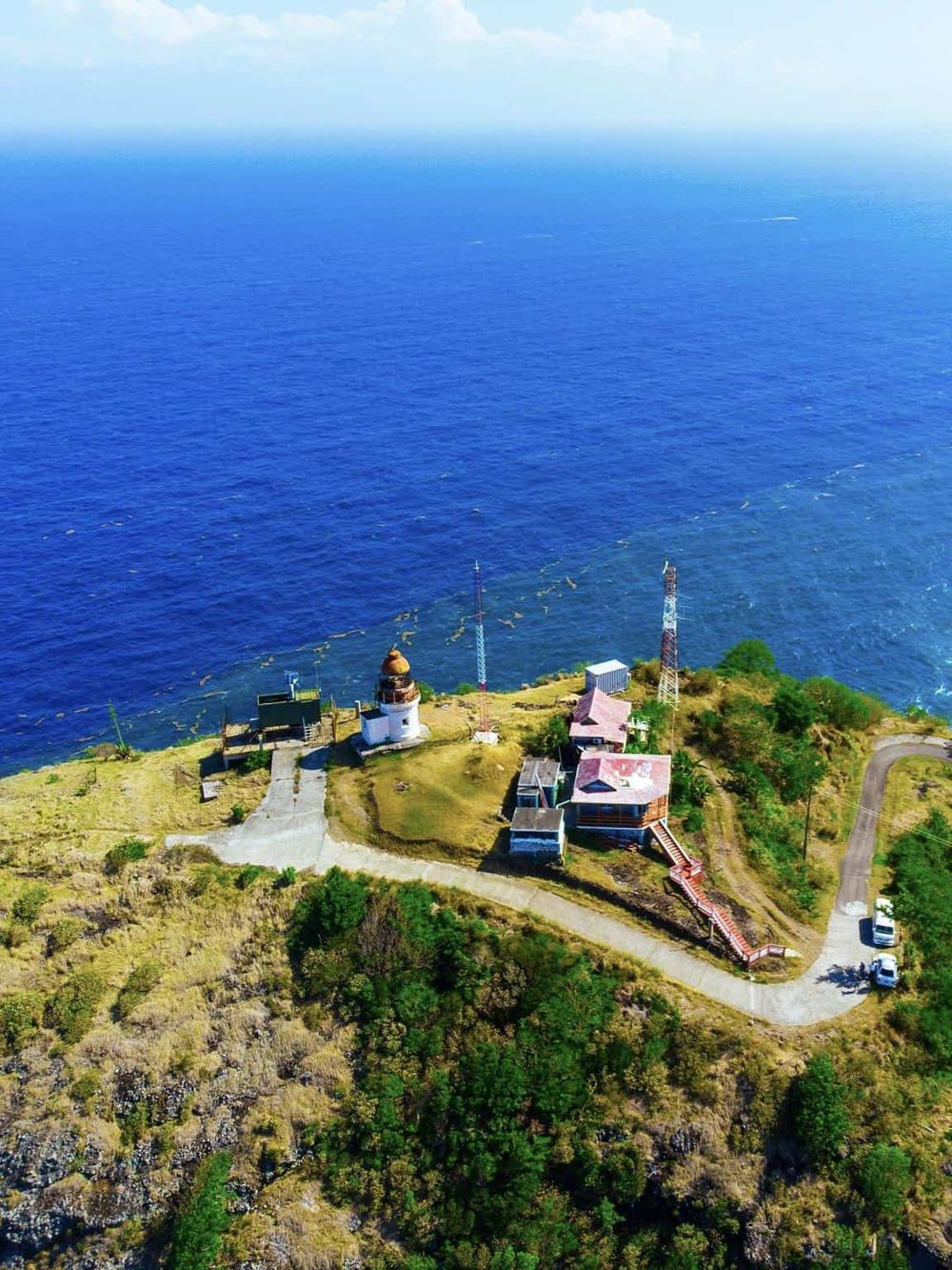 Vibrant blue ocean view at scenic lighthouse with surrounding greenery, ideal for travel and exploration.