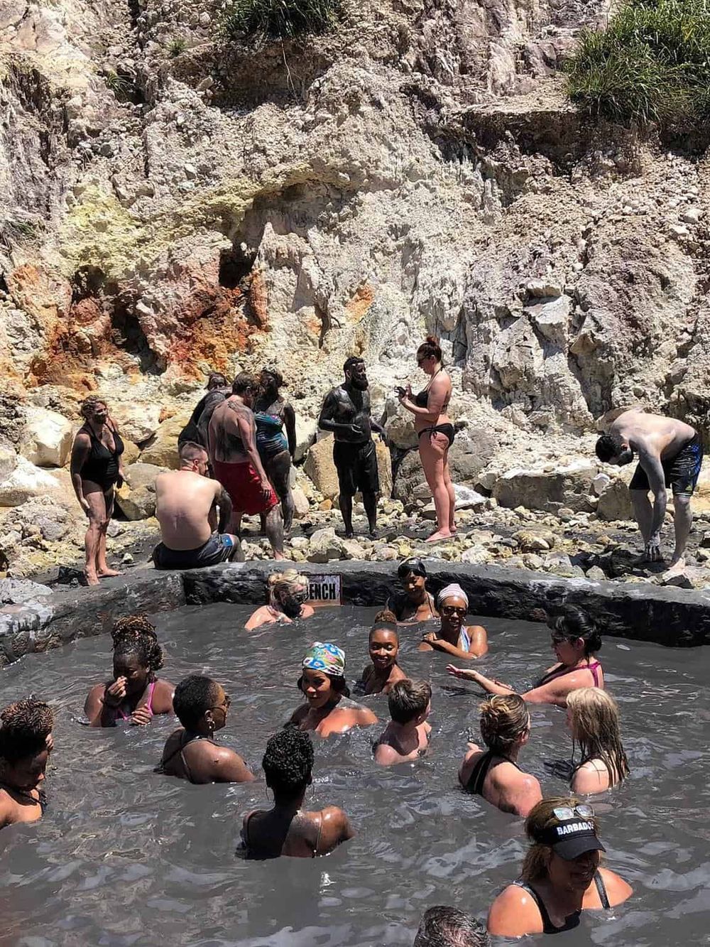 People enjoying a natural hot spring surrounded by rocky terrain, perfect for relaxation and outdoor adventure.