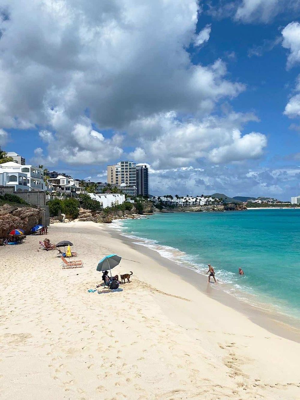 Vibrant beach scenery with white sand, turquoise water, and modern buildings in the background. Perfect for travel and vacation SEO.