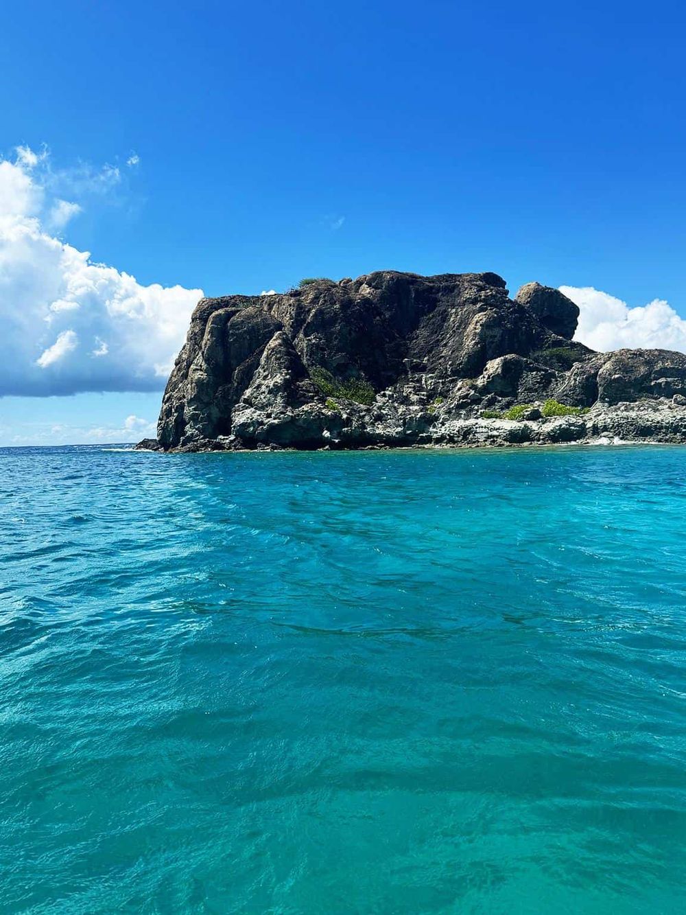 Striking ocean view with a rocky island under a bright blue sky, perfect for travel and adventure photos.