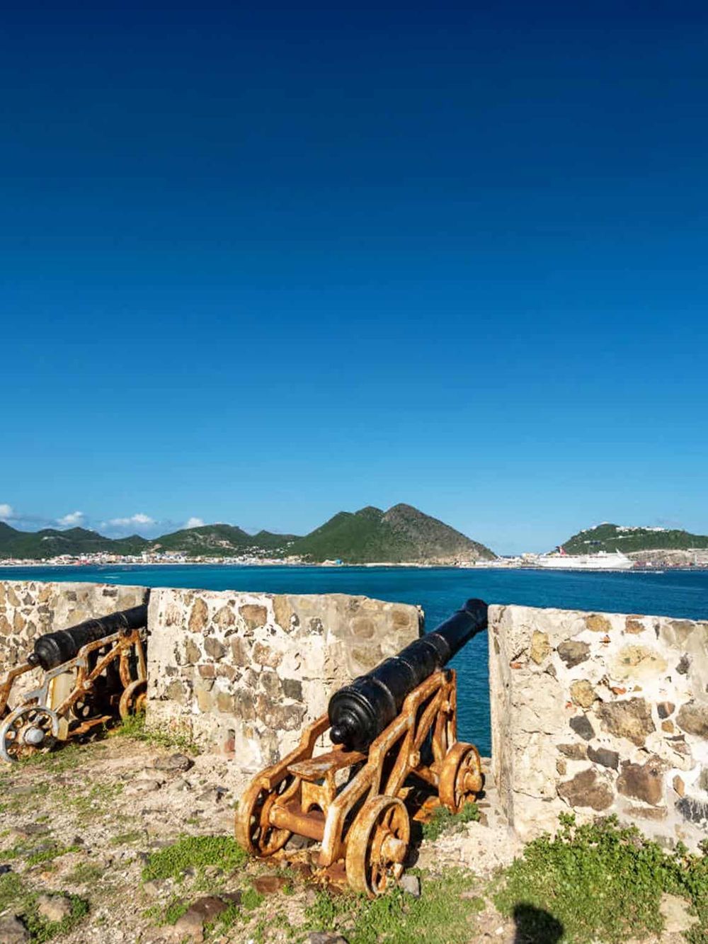 Colorful cannon and stone wall overlooking the harbor and lush green mountains. Perfect scenic view for travel and sightseeing in San Juan.