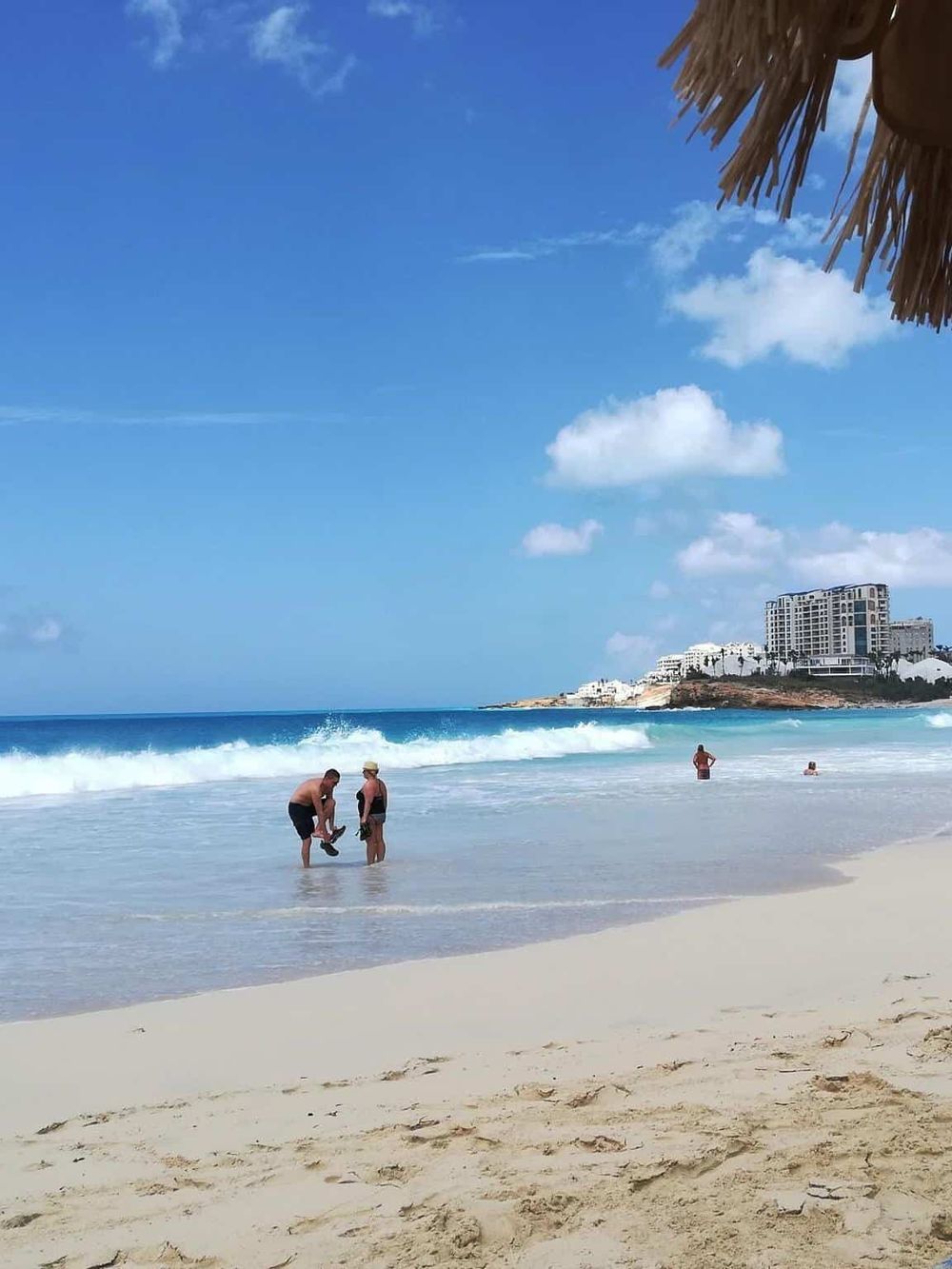 Stunning beach scene with clear blue sky, inviting ocean waves, and people enjoying the seaside.