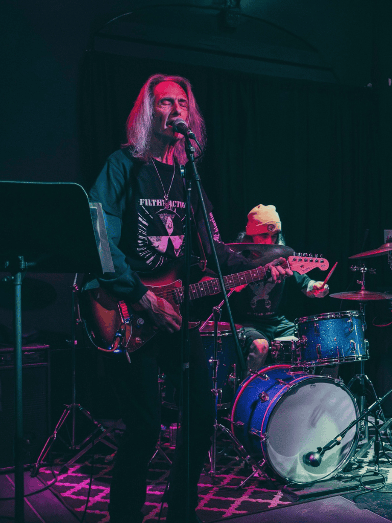 Energetic guitarist and drummer performing live music at QuestForDirections event.