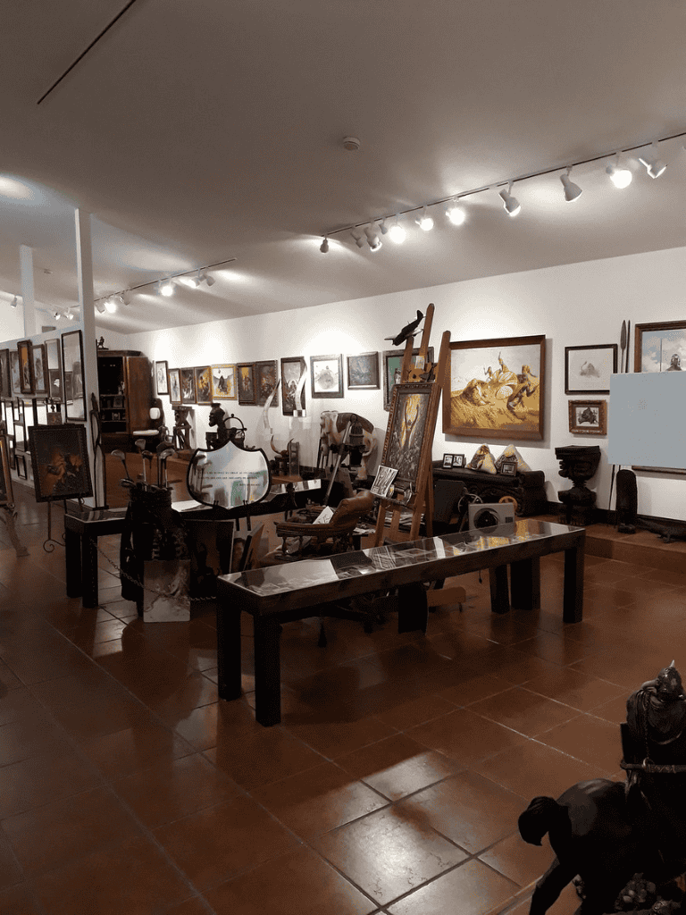 Antique art gallery with various paintings and sculptures in a well-lit room.