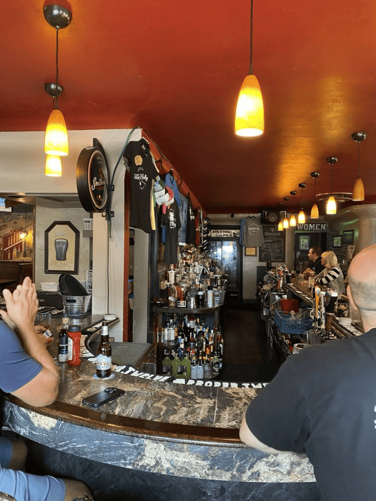 Cozy bar interior with liquor bottles and patrons, ideal for socializing and nightlife.