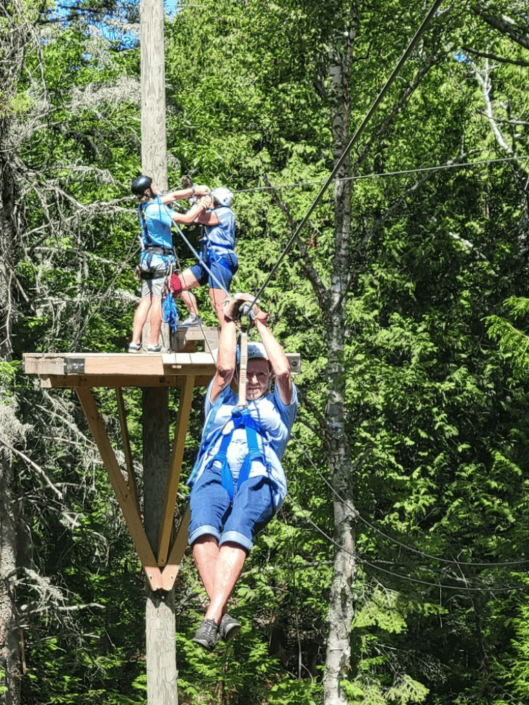 Adventure course zip line in lush forest with kids and adult participants.