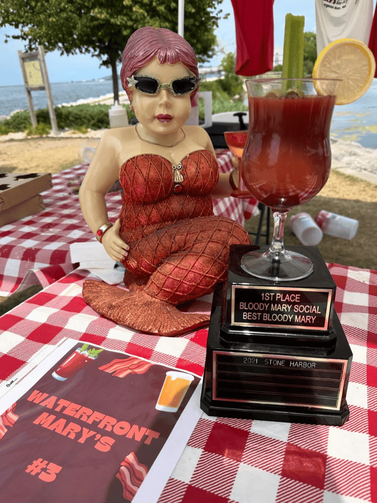 1. Quirky Bloody Mary trophy with mermaid figurine at outdoor waterfront bar.