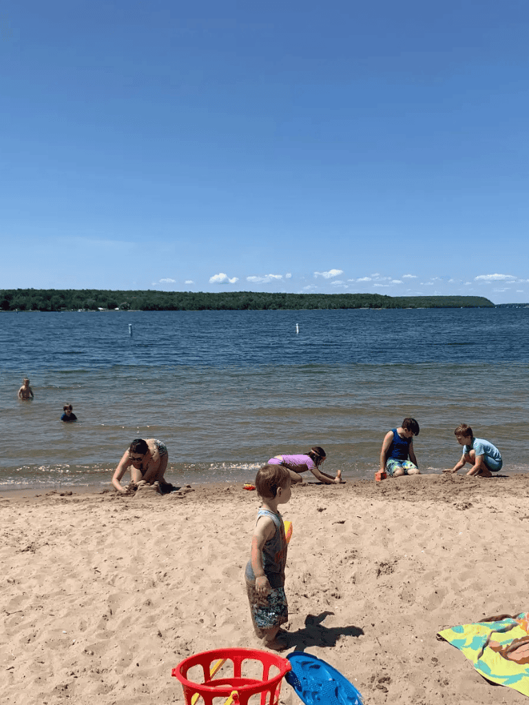 Children playing on sandy beach with water and scenic landscape at QuestForDirections.