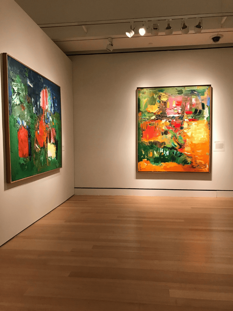 Bold, colorful abstract paintings displayed in an art gallery with gallery lighting.