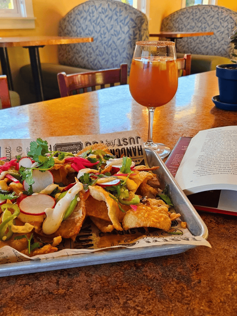 Colorful loaded nachos with fresh vegetables and a drink on a cozy restaurant table for a satisfying dining experience.