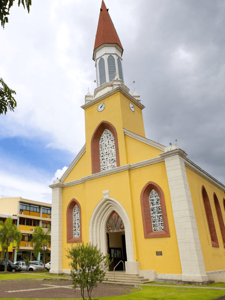Colorful historic church with yellow walls and red accents in QuestForDirections setting.